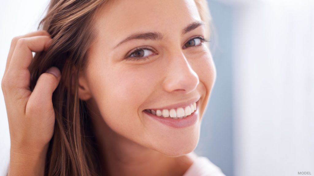 Woman looking forward running hands through hair (model)